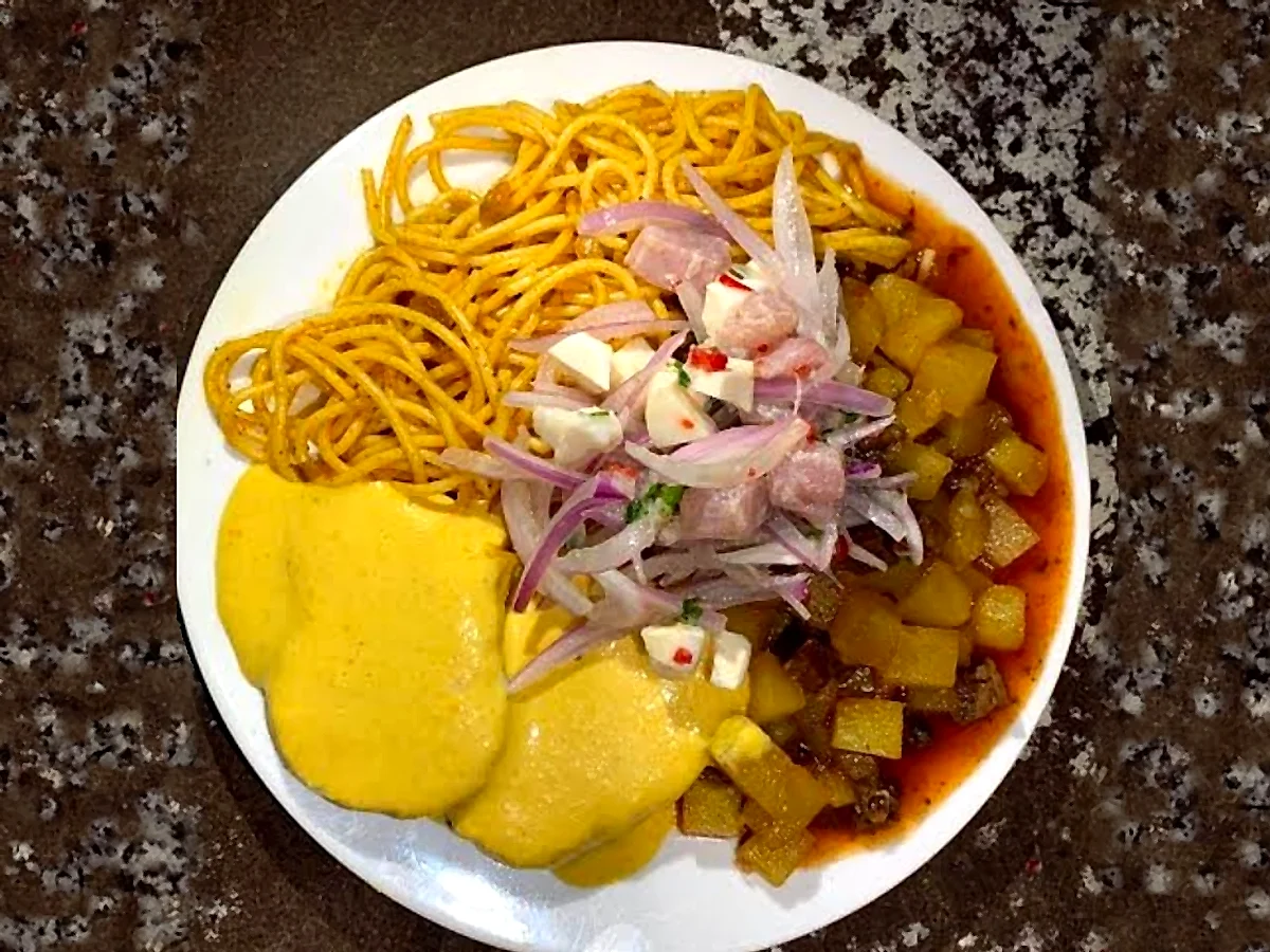 Plato de chanfainita con tallarín rojo, papa a la huancaína y ceviche